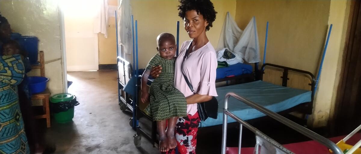 Benedicte holds Jusline in one of their first meetings. Barely able to walk, with exceedingly swollen feet and painful sores, the initial two weeks of therapeutic milk and food saw her body respond and begin healing with encouraging results.