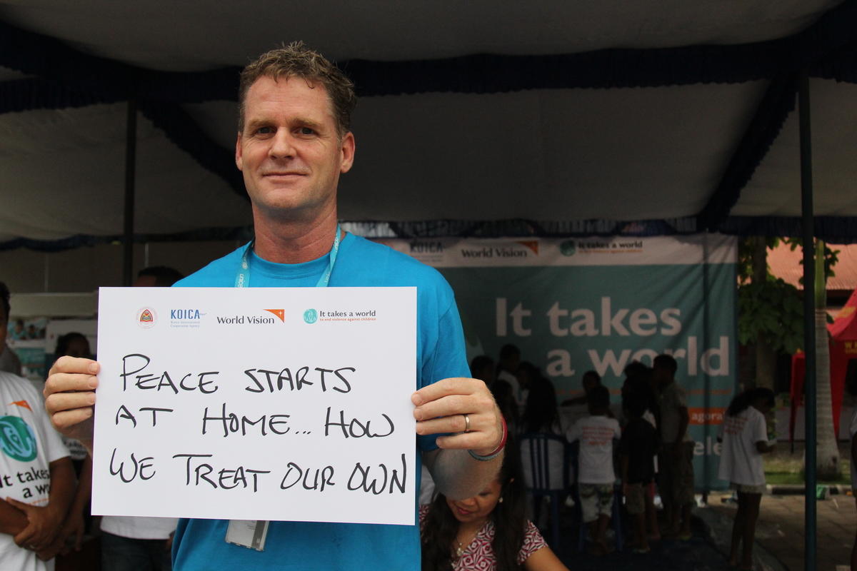 UNICEF Deputy Director holds a sign saying peace starts at home how we treat our own