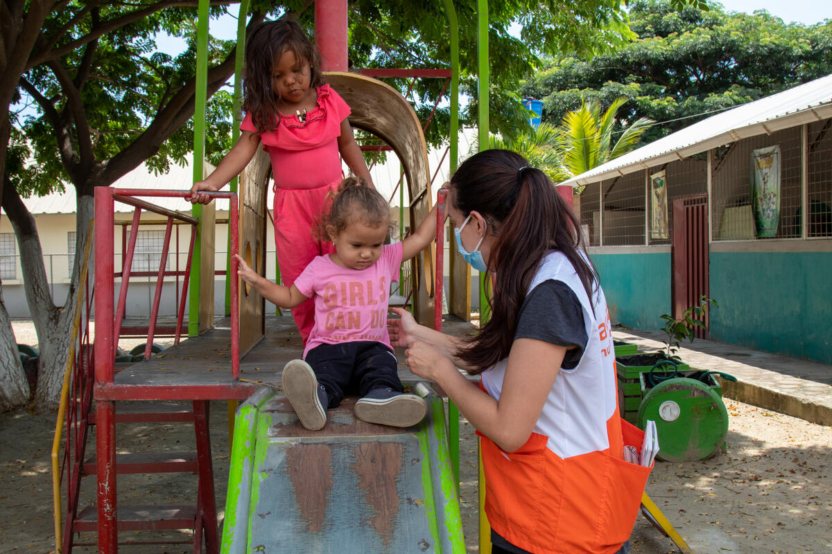 Isabela plays with a World Vision staff member as her mother receives support.