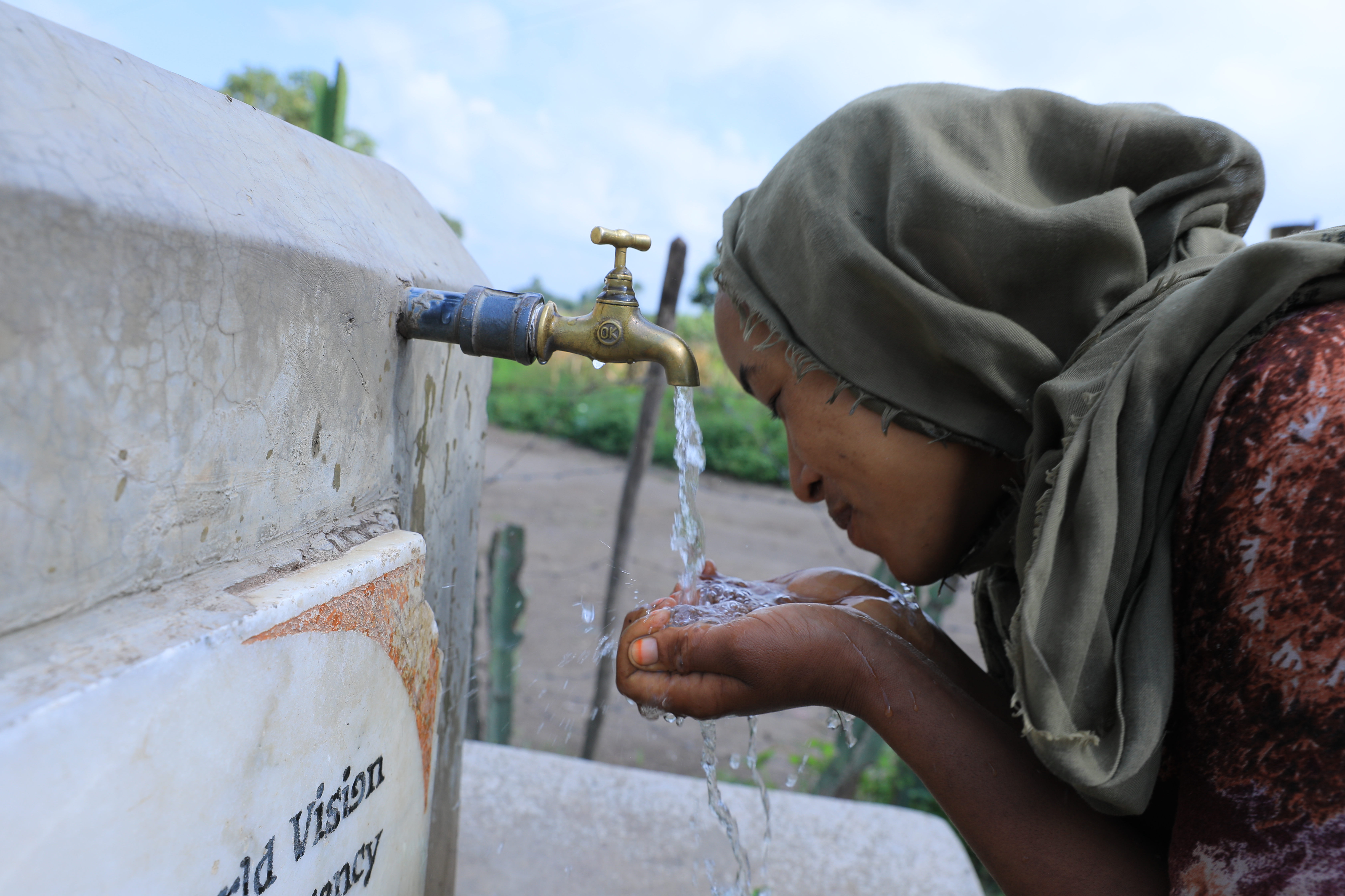 A lady from Shashemene in Ethiopia drinking water from  a World Vision installed water point in her area