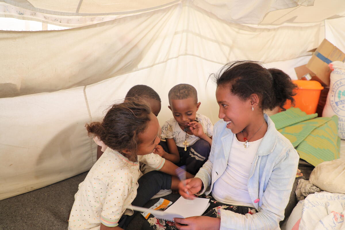 a young girl plays inside a tent with other children
