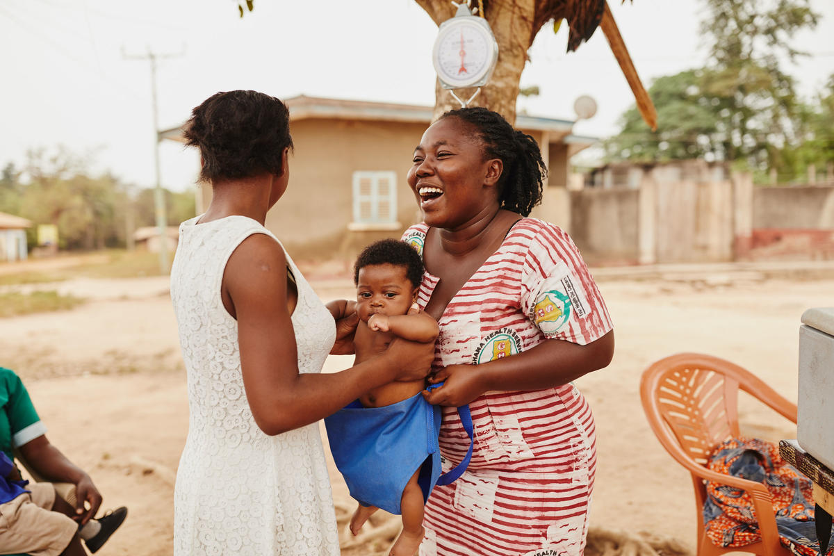 Women in Kenya weigh a young child to check for malnutrition