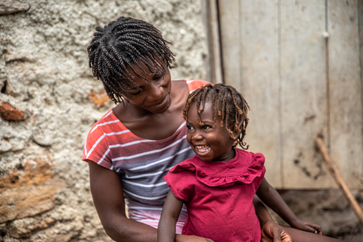 Schamaelle sits on her mother Westa's lap in Haiti. Thanks to food vouchers, she is growing healthy and strong/