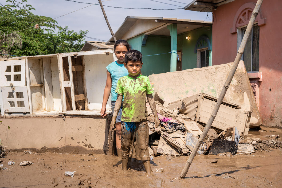 Children stand in the mud outside their home in Honduras following two hurricanes.