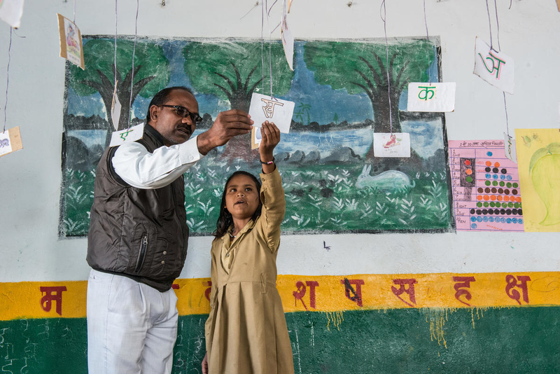 A teacher and child look at letters