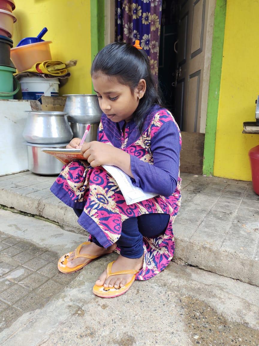 sponsored child in India sits on the step of her house