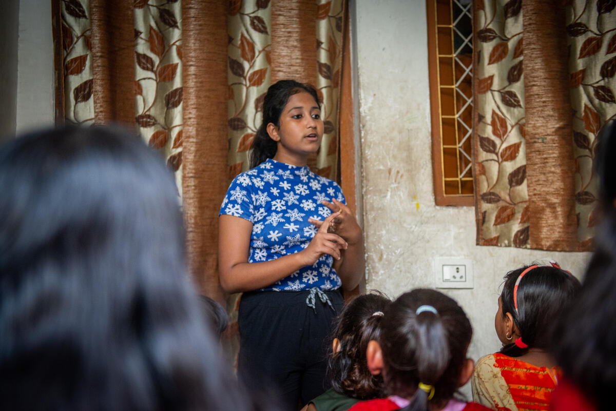 girl stands in front of a group of children giving a speech