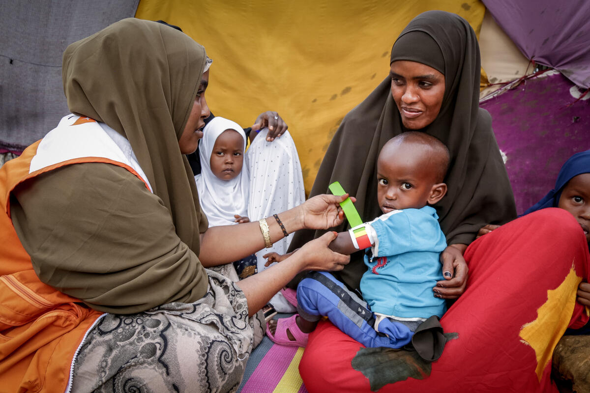 World Vision staff member measures a child's arm for to screen against malnutrition and/or take action early to prevent lasting consequences.