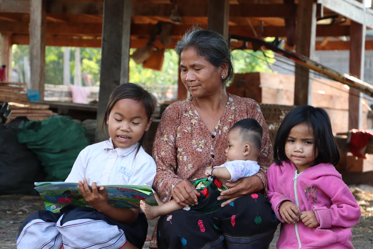 Kam reads to her grandmother and siblings in Laos.
