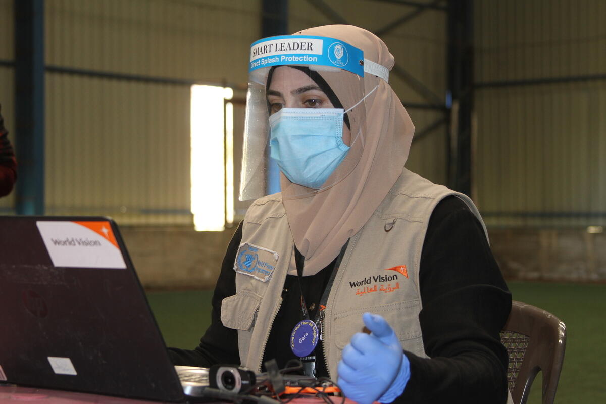 World Vision staff with mask and laptop