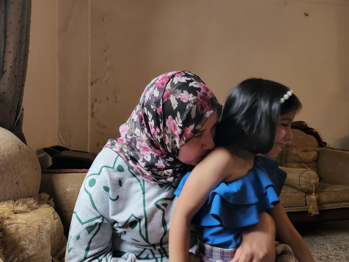 Safaa kissing her daughter's shoulder at their home.