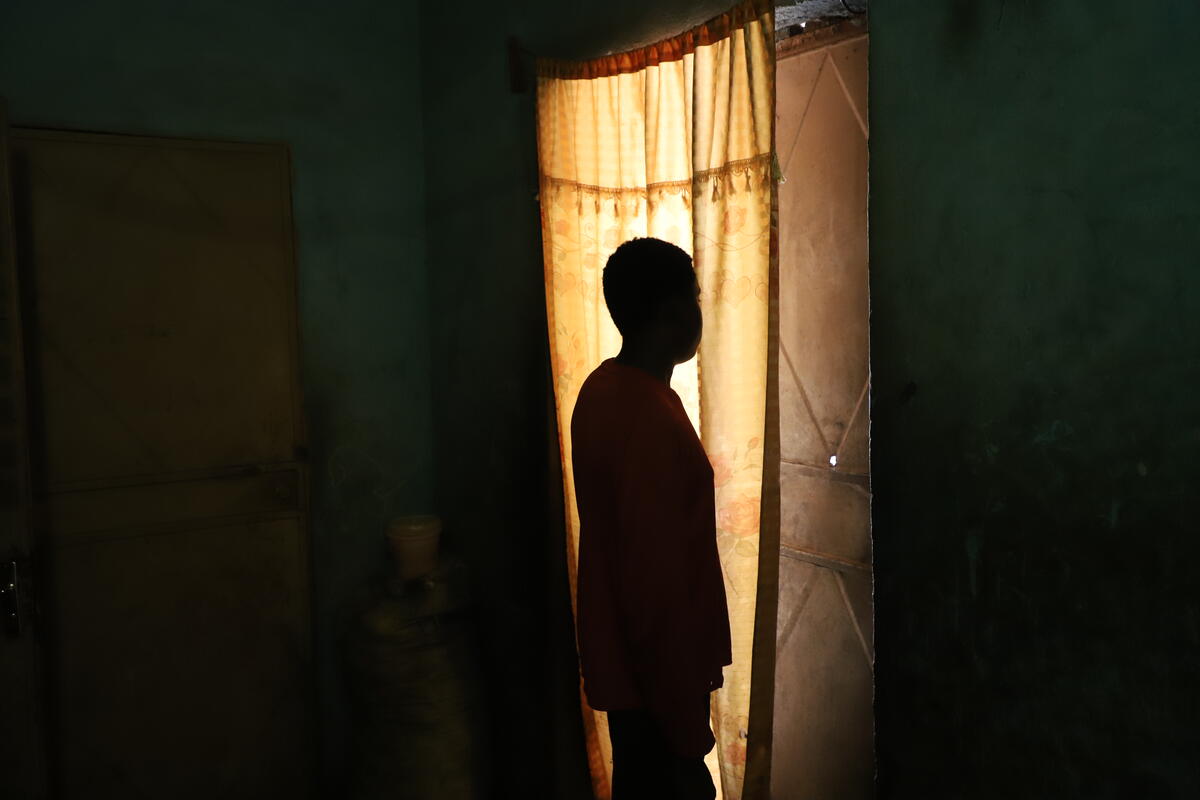 A boy standing in his home, in a reflective manner of his past experience