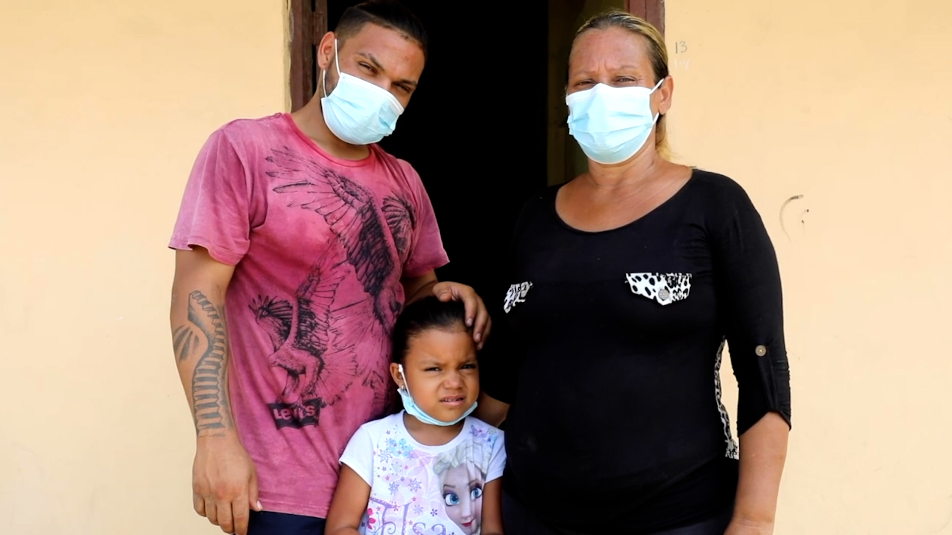 Ami with her father and grandmother outside their home.