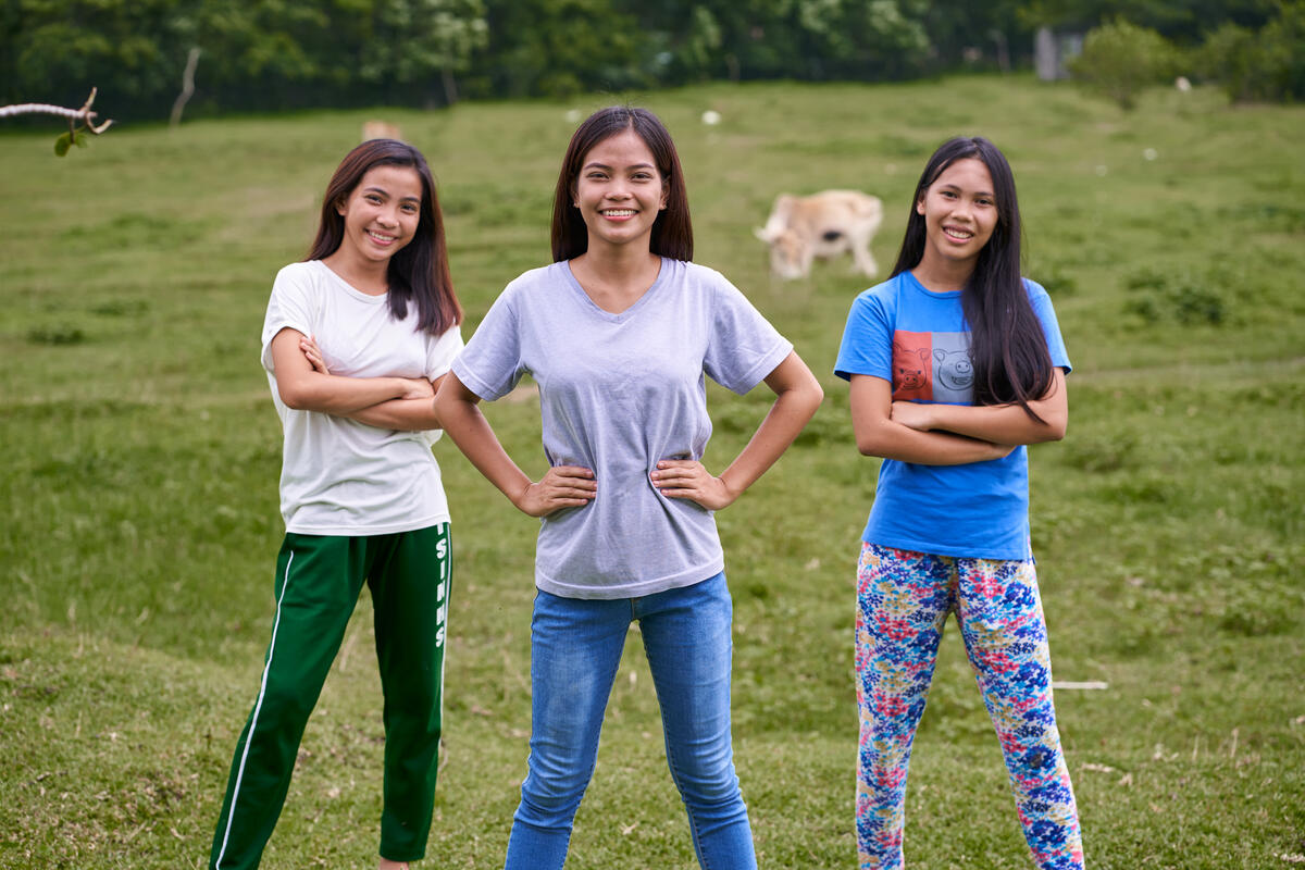three girls stand in a field smiling 