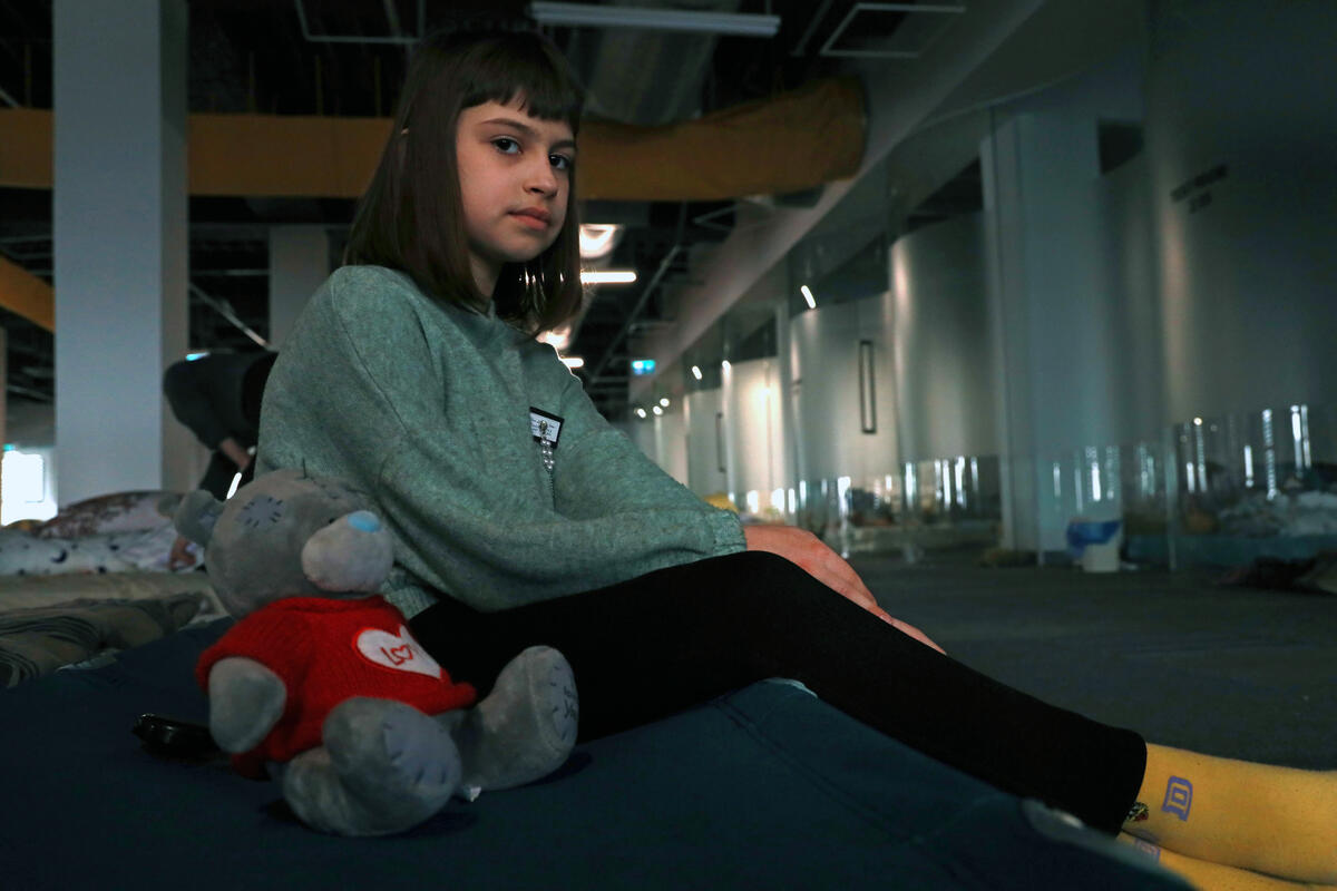 Viktoria a young refugee from Ukraine sits in on her makeshift bed in a warehouse in Romania