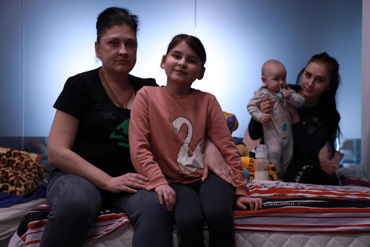 Diana 9 sits with her mother on a bed at a transitional shelter for refugees coming from Ukraine, in Romania.