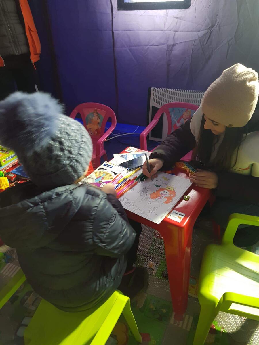 Andreea helps a small child with drawing