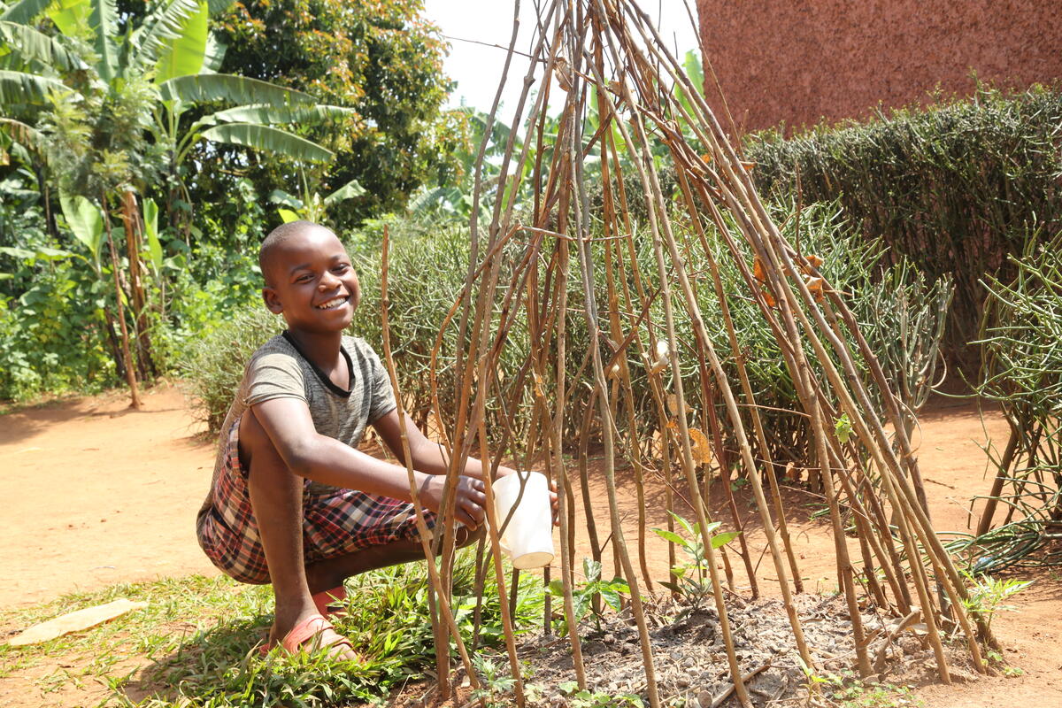Thierry 11, is World Vision’s sponsored child watering a fruit planted in his compound.