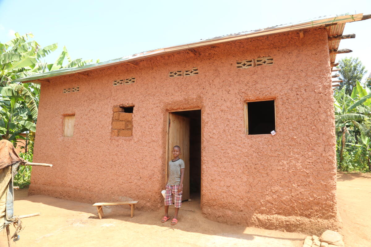 Sponsored child stands in the doorway of his family's first home.