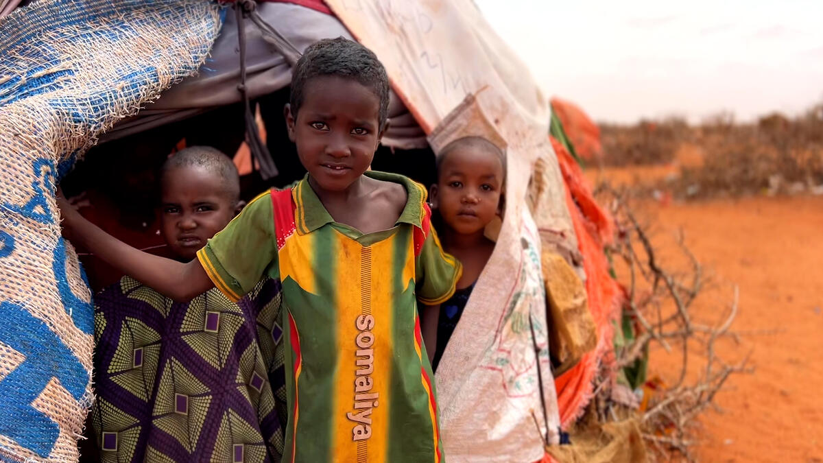 Children stand in their tent