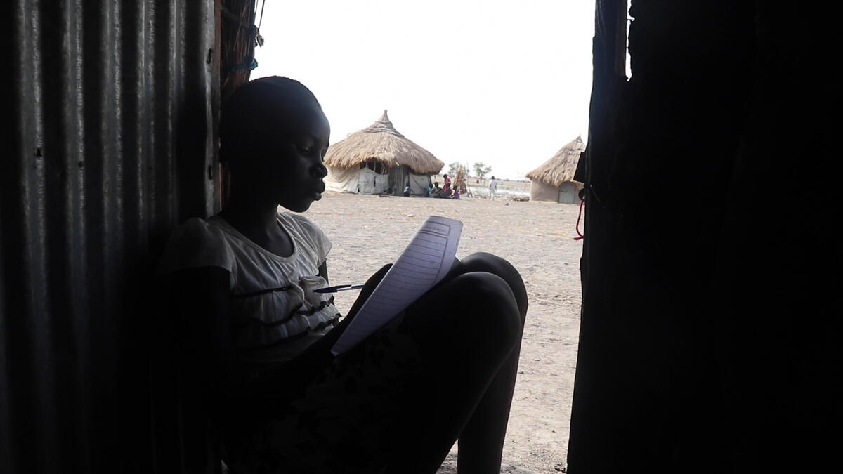 Young girl studies in doorway in South Sudan