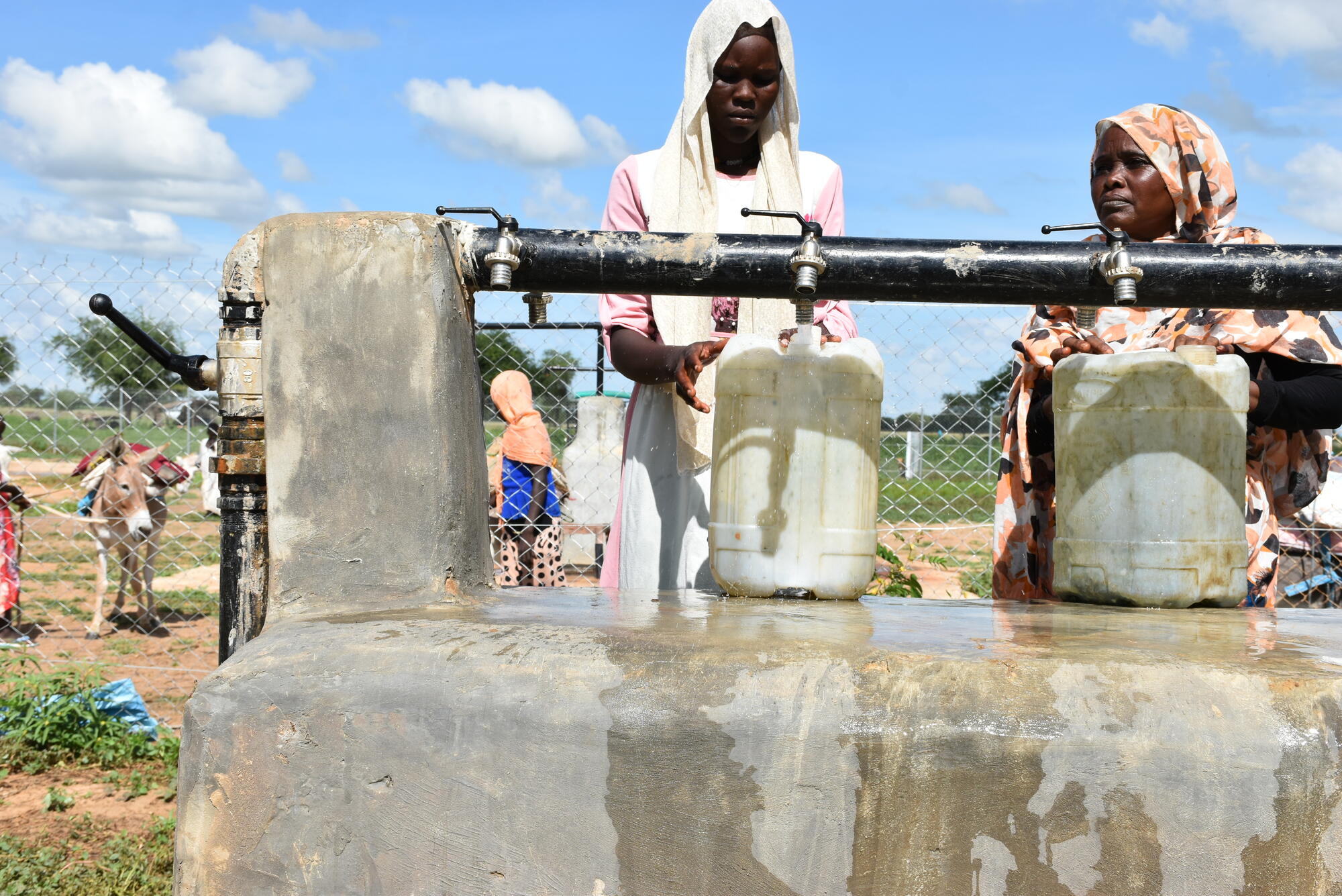 Girl and woman fetching water at a water station provided by World Vision 