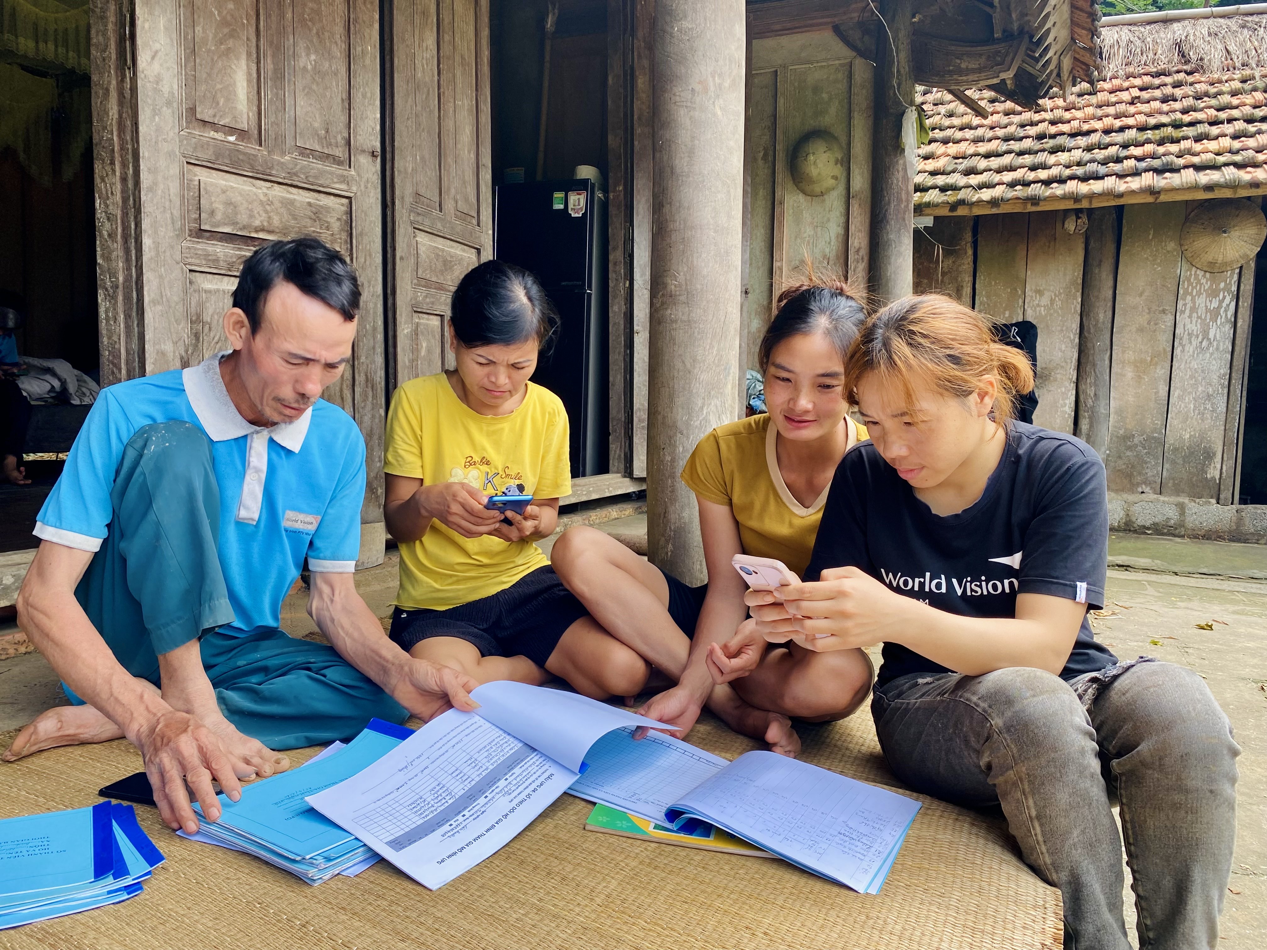 A child in rural Vietnam learns to use a mobile phone while reviewing school materials during a World Vision activity.