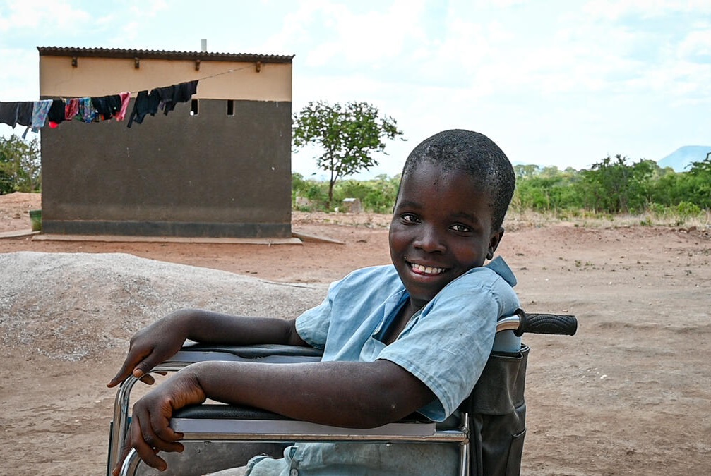 13-year-old Mary in Zambia sits in her wheelchair smiling at the camera
