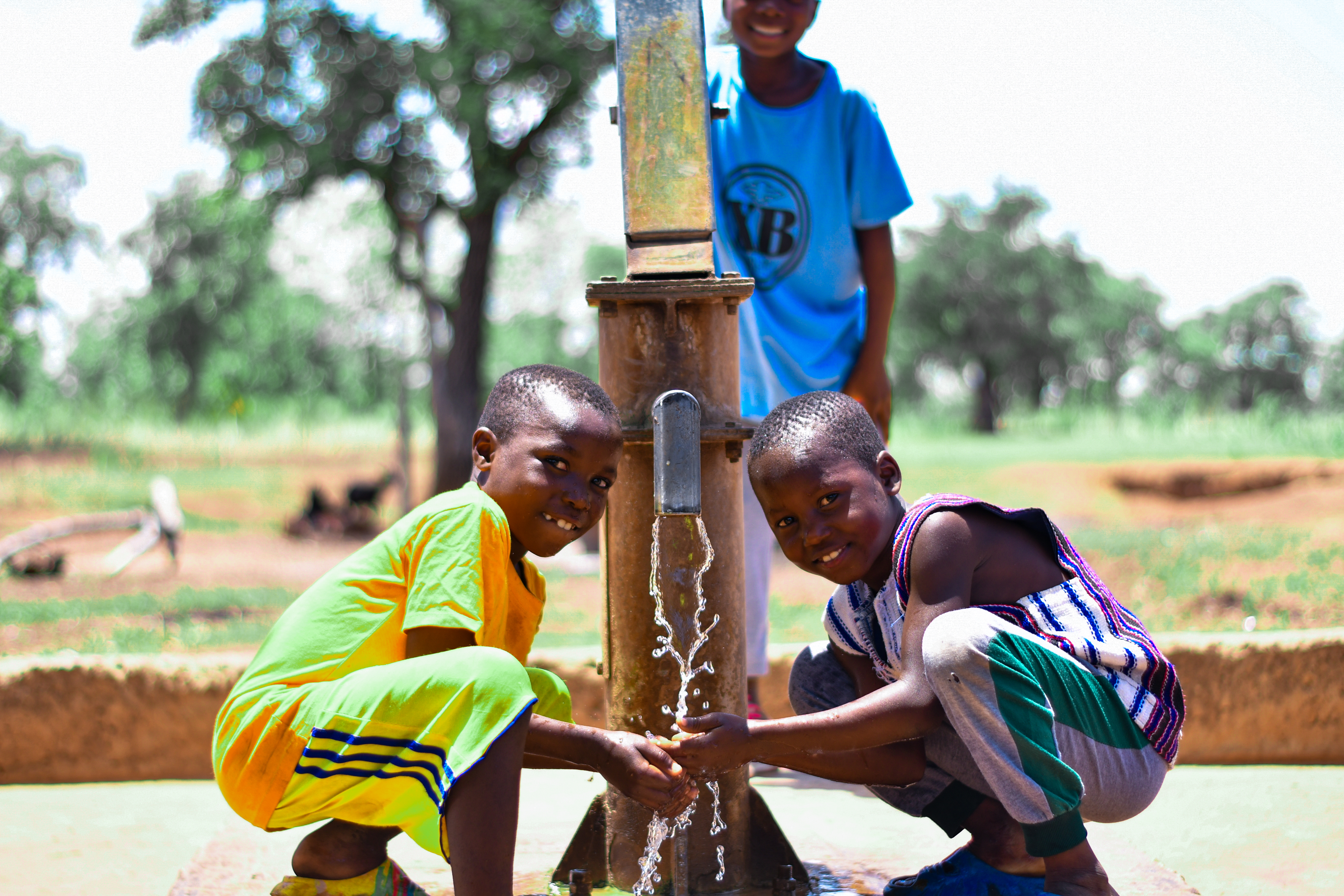 Two children drinking water from the tap. 