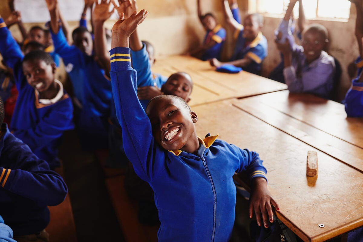 children happily raising their hands in class