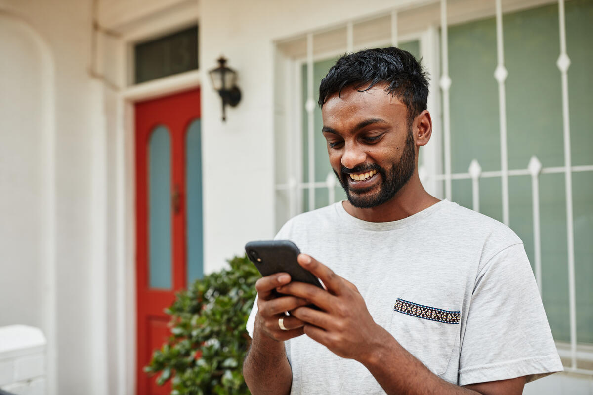 Young man uses cellphone as he stands outside