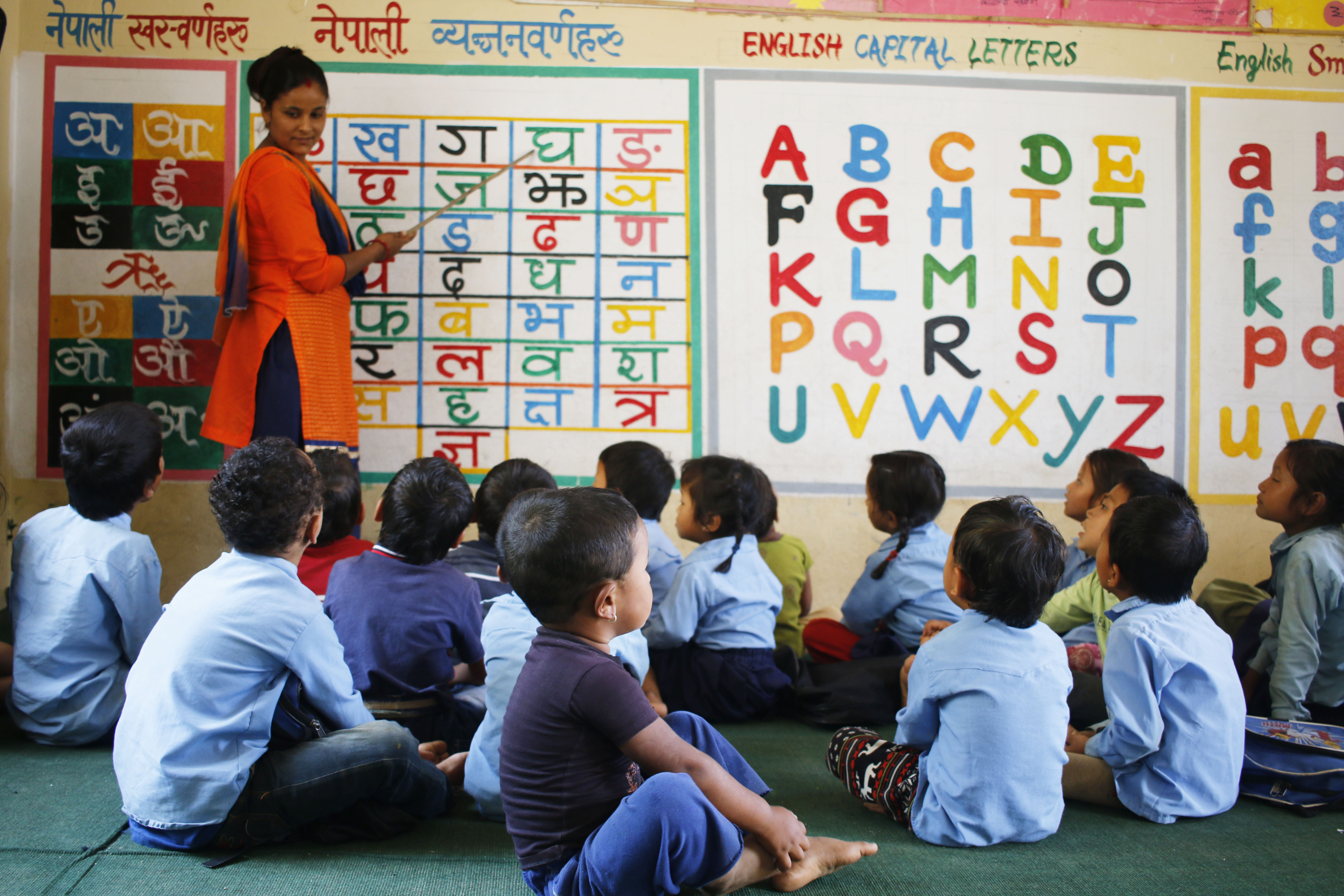Subista (standing) leads her students in a letter-reciting activity.