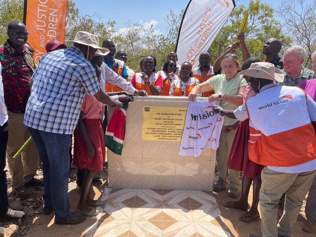 The World Vision team and donors are flanked by Kenya government officials during the unveiling of the plaque for the new school