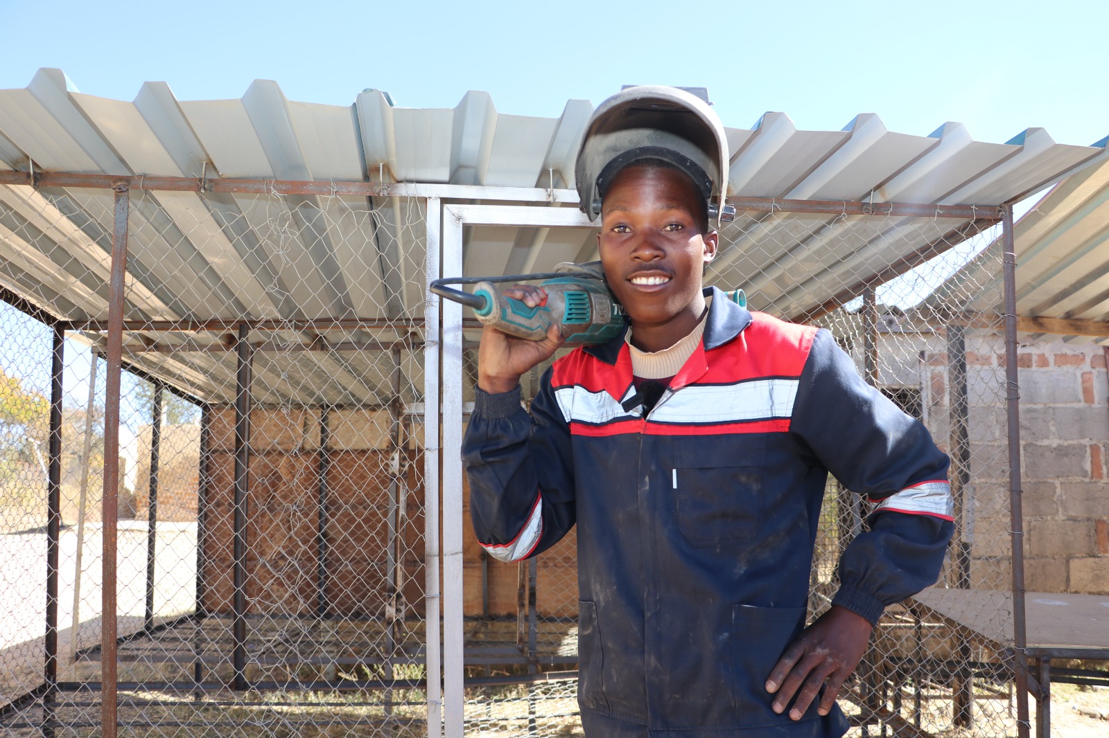 Tapiwa proudly stands in front of the chicken foul run he designed