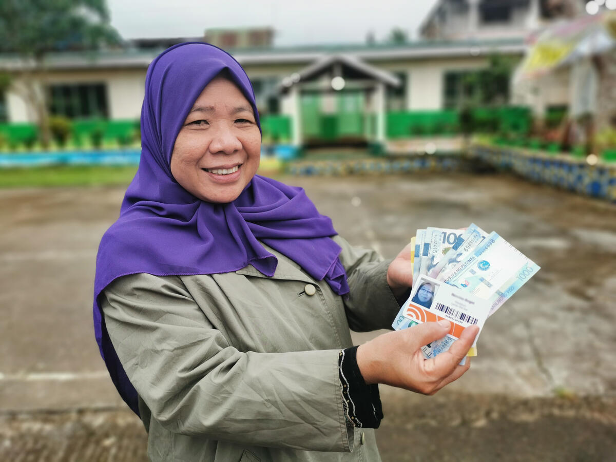 Woman from Indonesia wearing a headscarf holding money