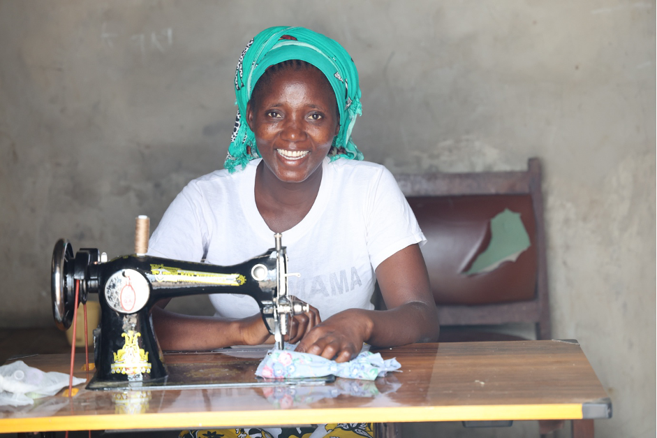 Farida is in her Tailoring Shop. She utilized the knowledge from World Vision trainings to purchase the sewing machine using the money from the S4T group.