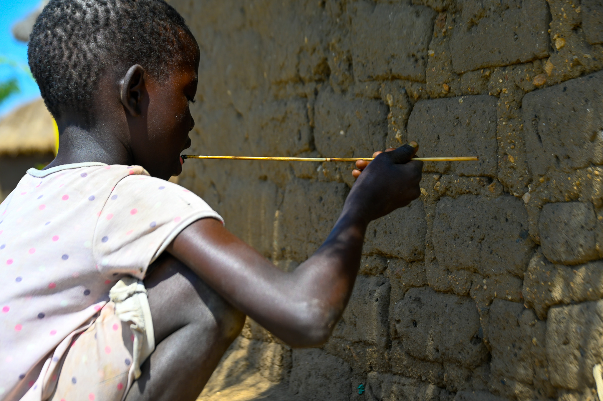 Nensa mixing a few edible leaves and water her attempt to make a meal. © World Vision Photo/Mungu Jakisa Brian