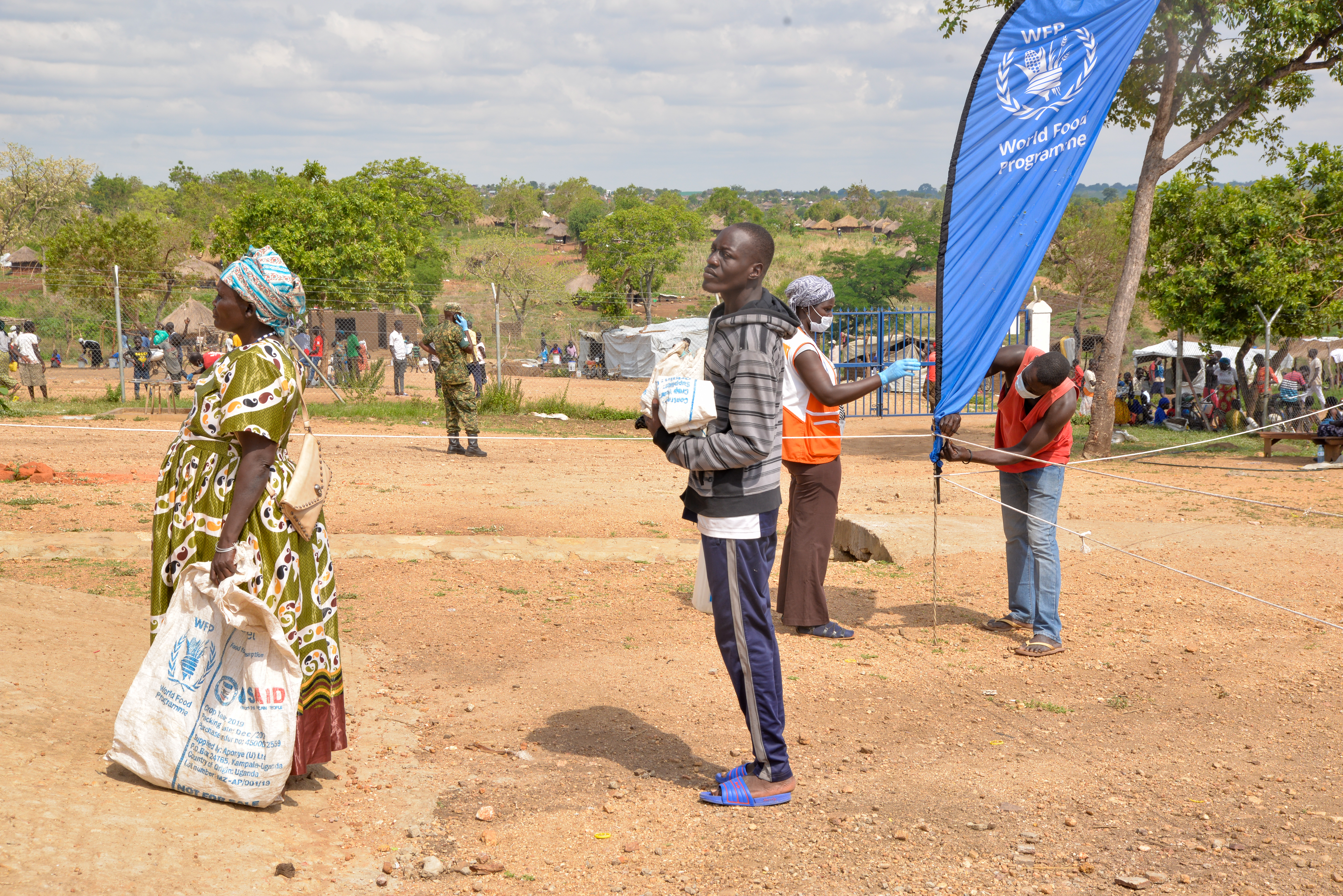 Refugees lining up to get food, with at least one metre distance between them