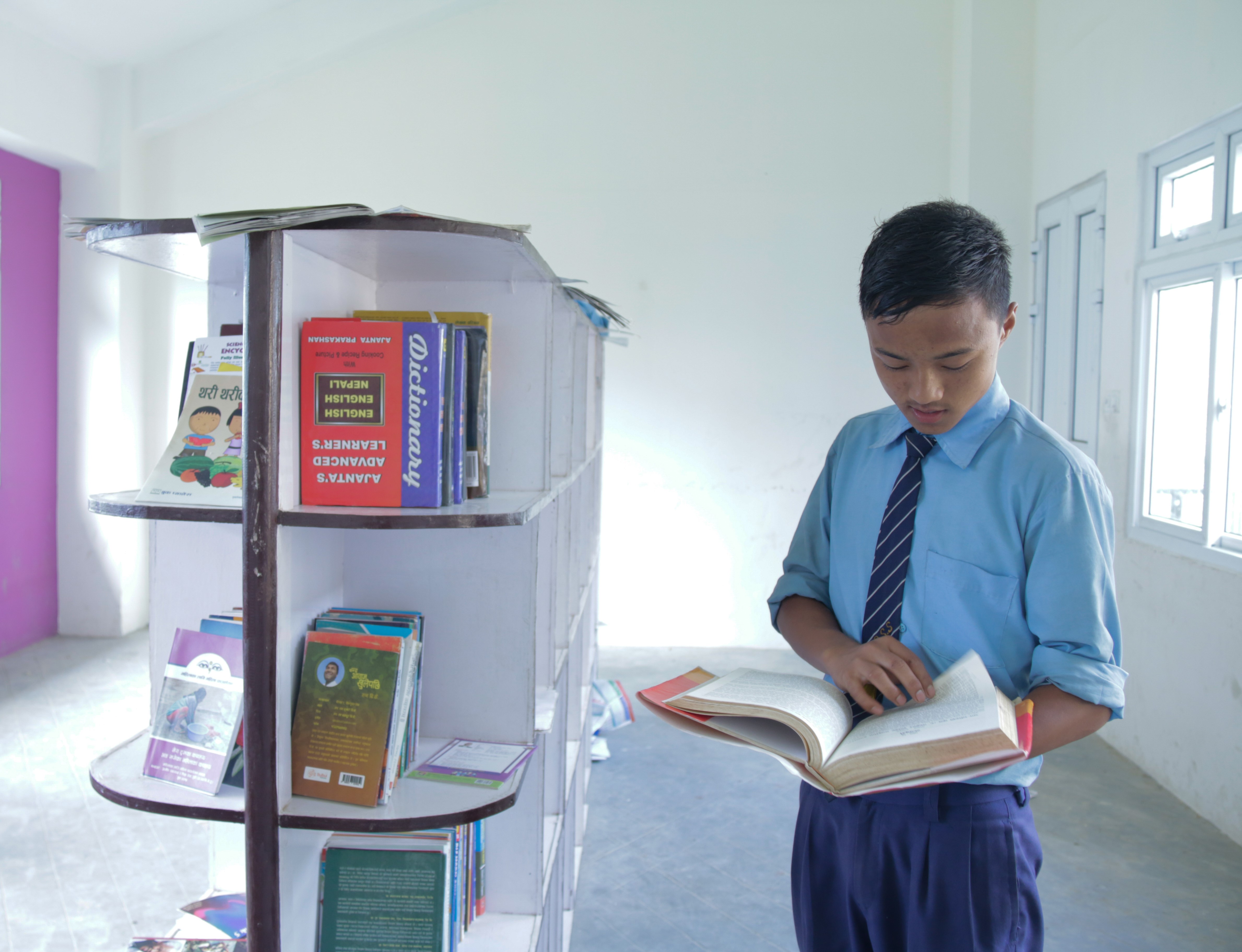 Manoj reads through a book in his school library 