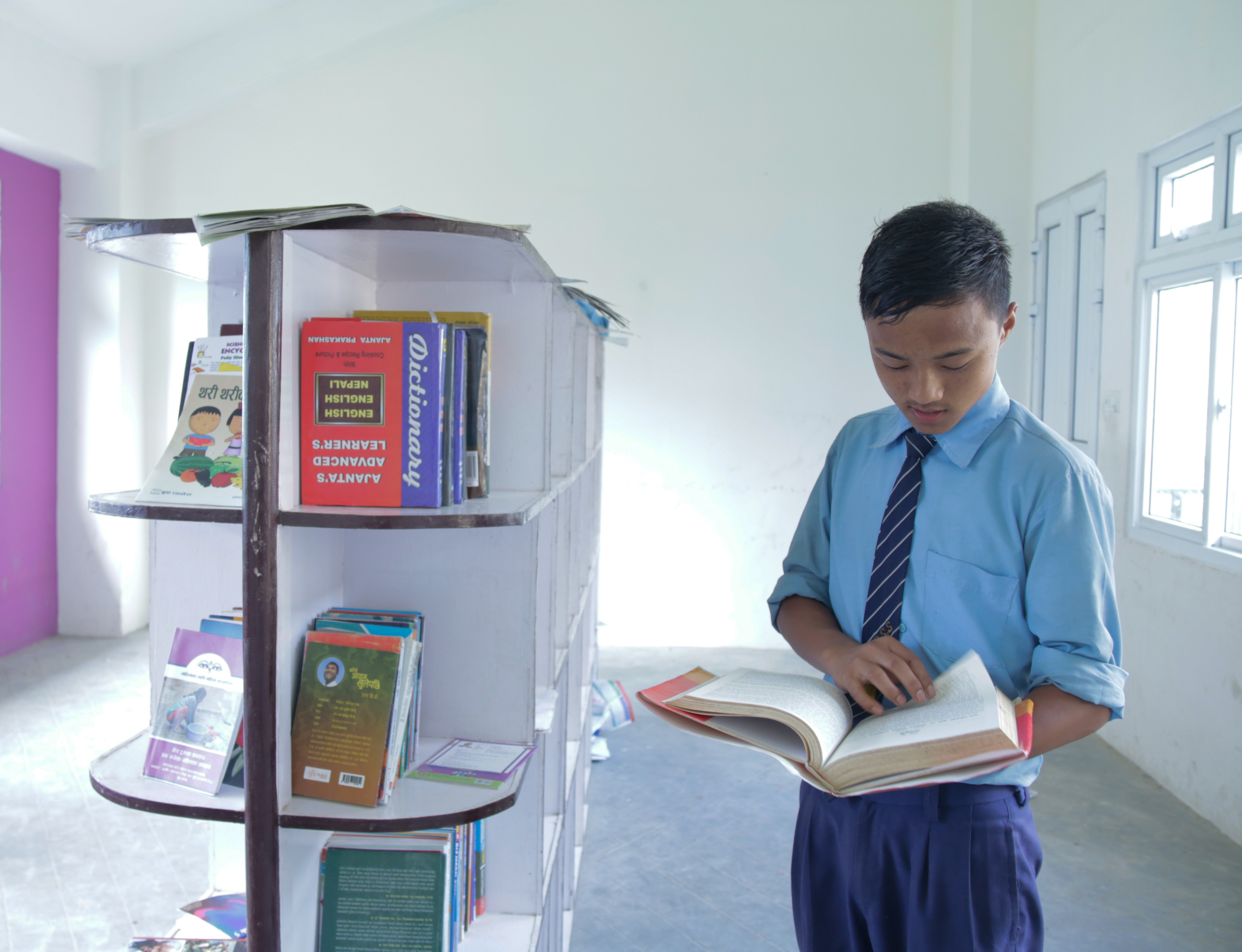 Manoj reads through a book in his school library
