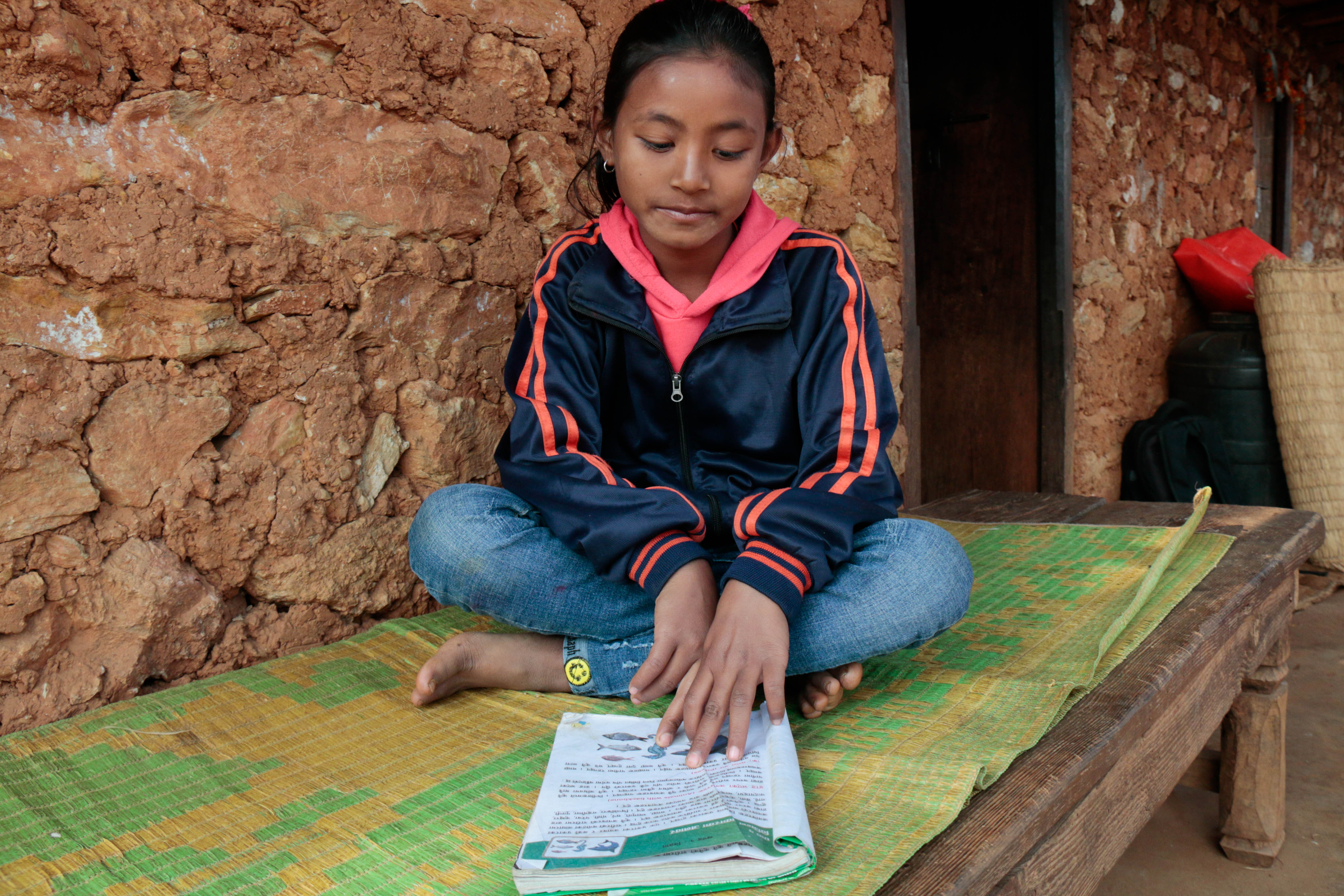 Hisila reads her course book as her daily morning routine