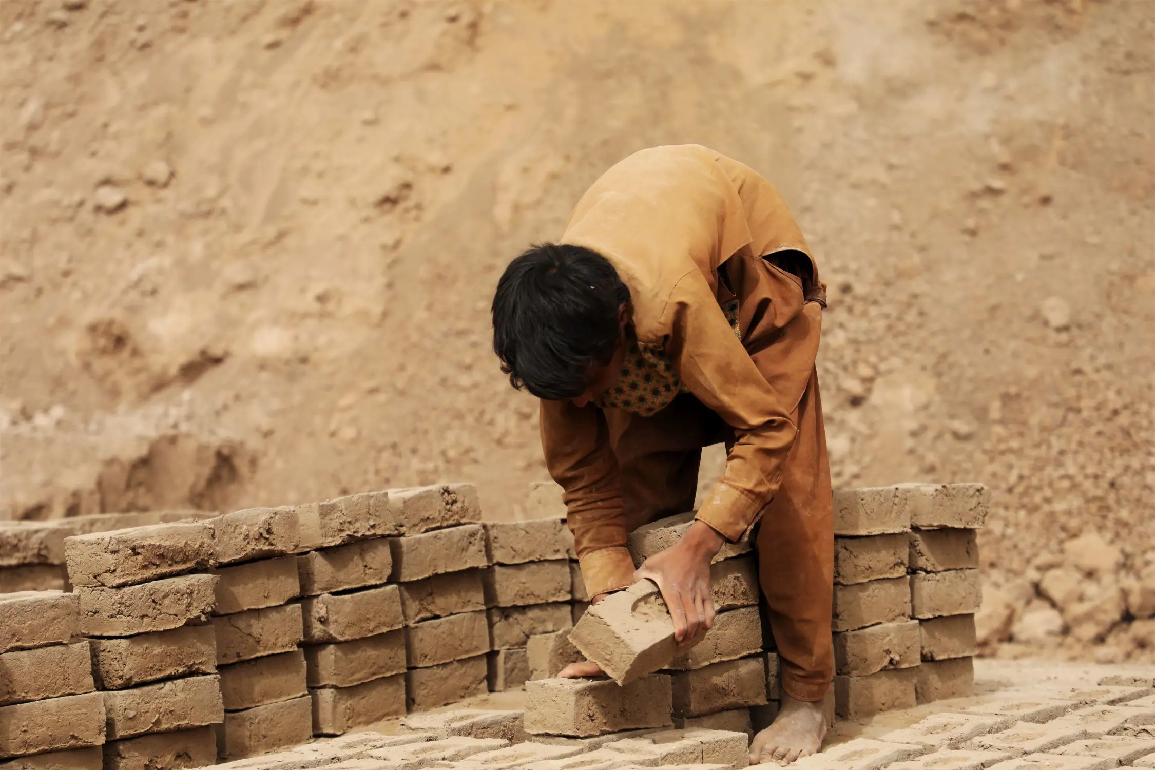 A child in Afghanistan making bricks