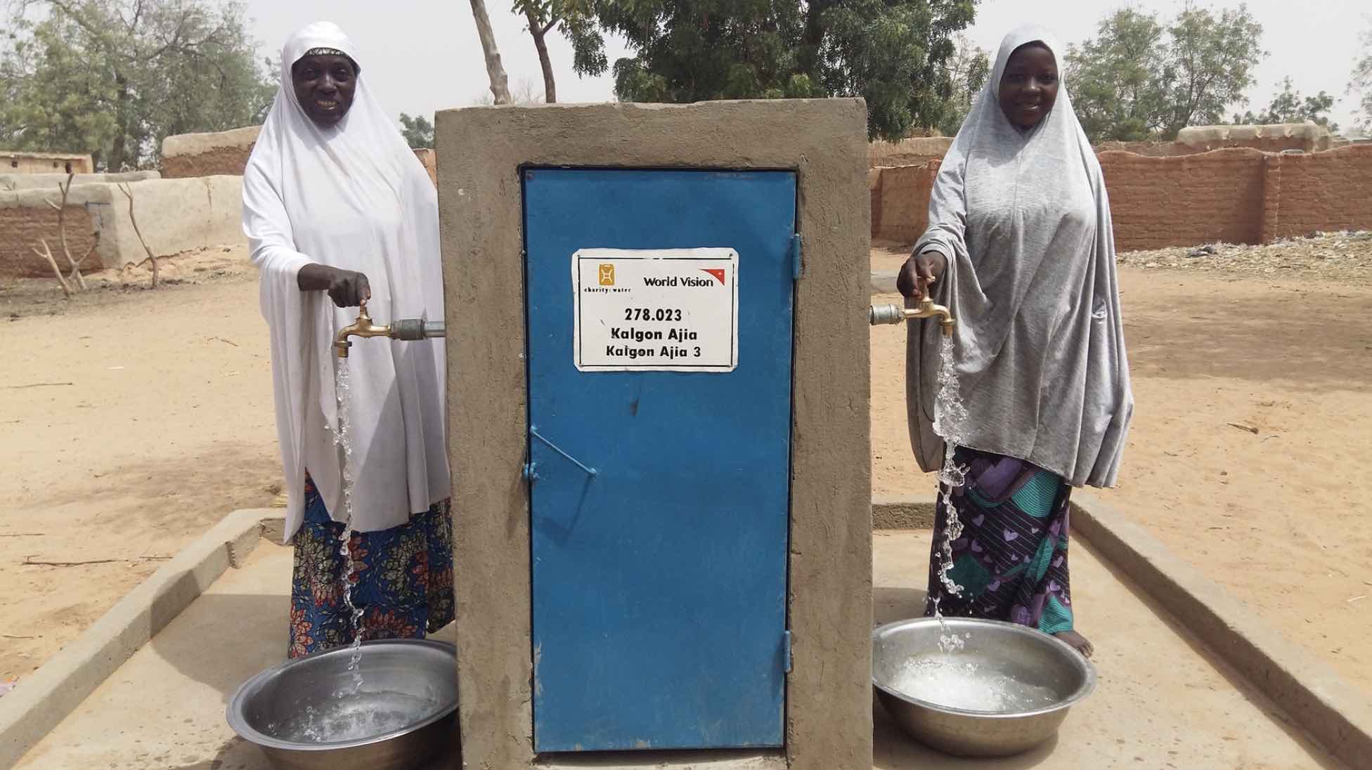 Two people benefitting from piped water