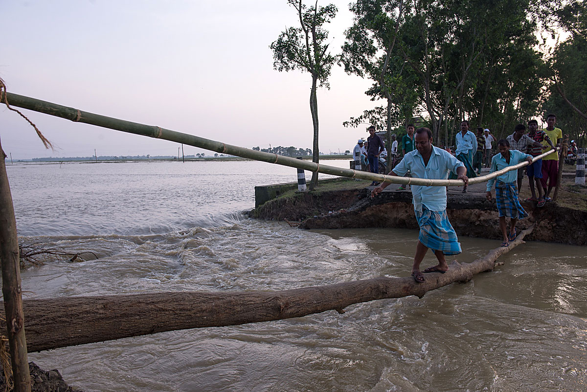 People crossing a bridge in flooded India