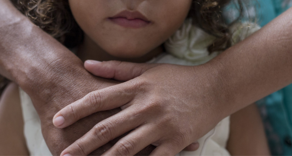 young girl with adult hands around her