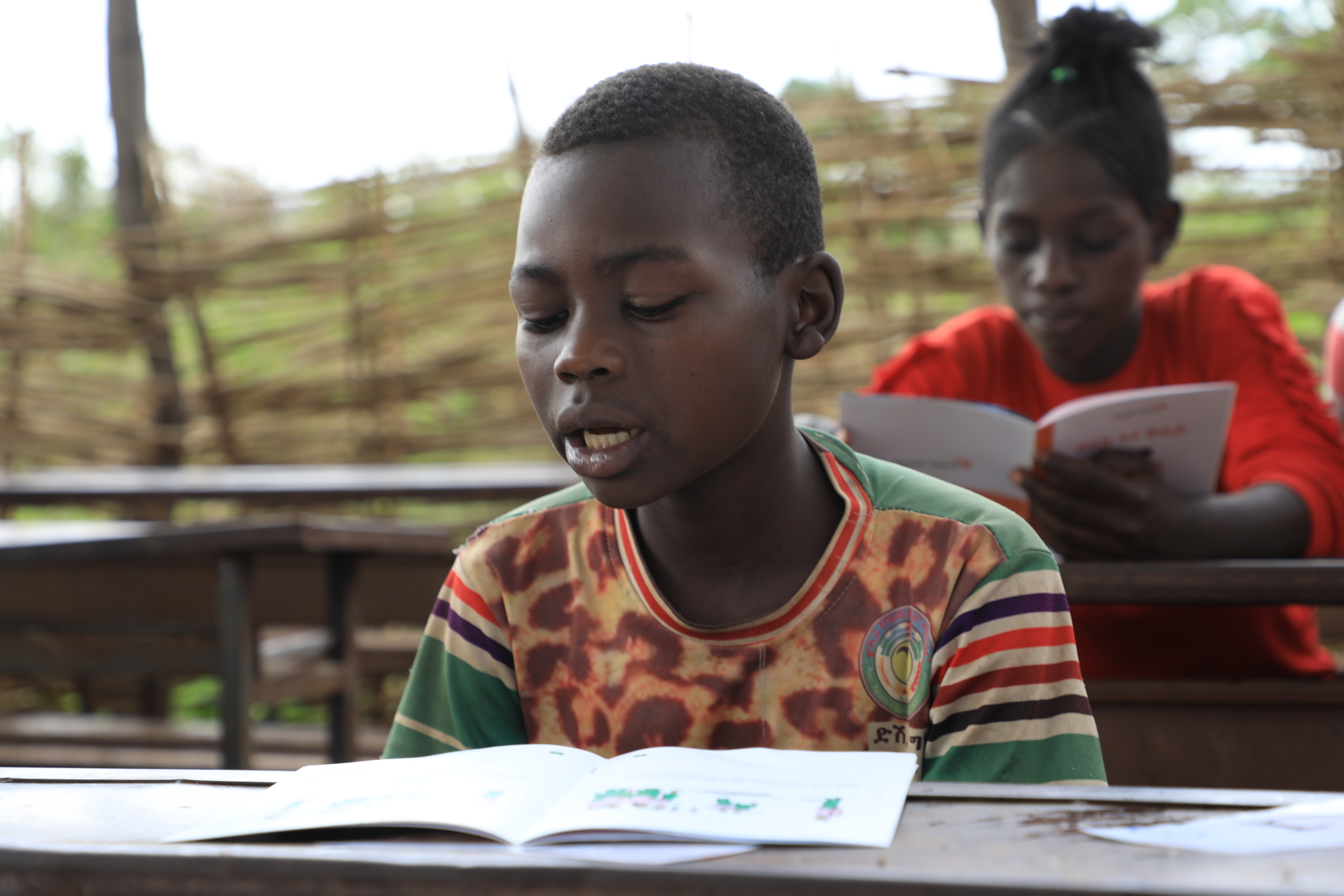 Abenezer reading a book at his desk at the reading park