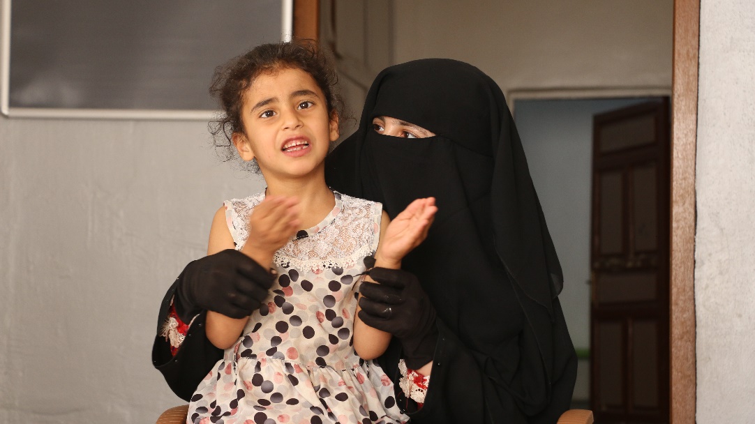 Zahra* claps along to the music beside her mother at the Child Protection Centre. World Vision Syria response partner