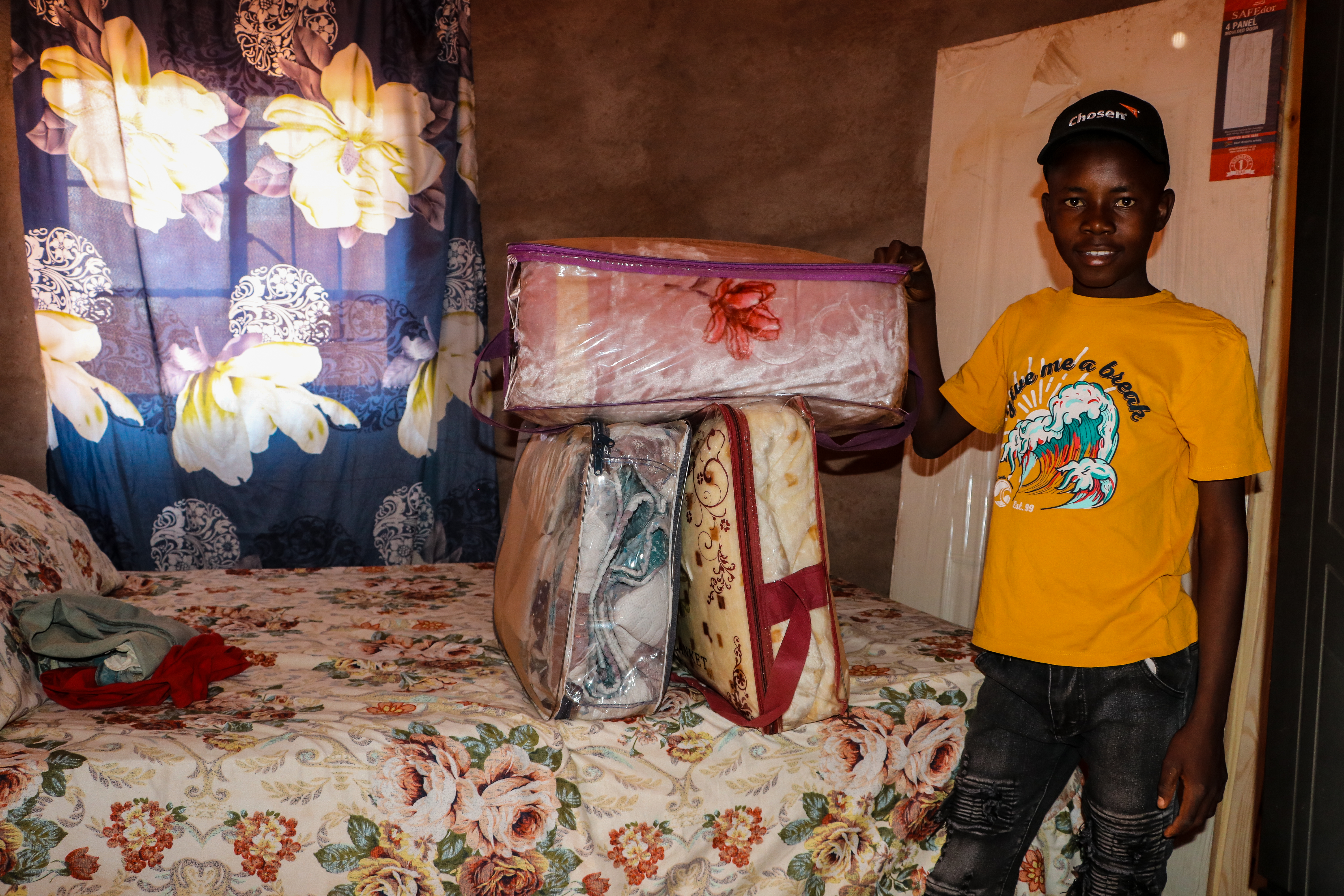 Inside the bedroom he built, Sydney proudly displays the bed, linen, and wardrobe he was able to buy thanks to the GNs from his sponsor.