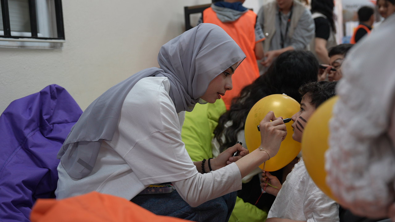 Sara volunteering as a facilitator at the LIFT centre, with face painting children and bringing smiles to their faces.