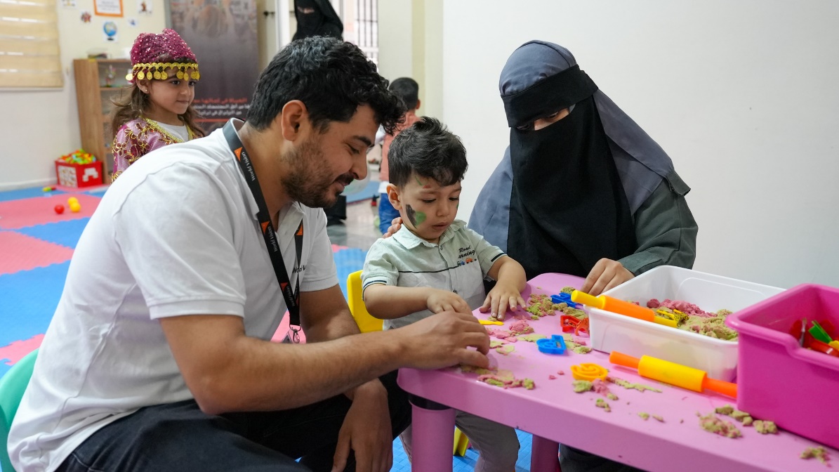 Hamza interacts with his mother and Muhammet Ali, the child development facilitator — shaping together, piece by piece, learning as they go.
